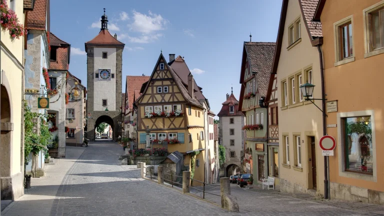 Ngôi nhà gỗ hẹp màu vàng nằm giữa hai cổng thành Trung Cổ tại góc ngã ba Plönlein ở Rothenburg Đức