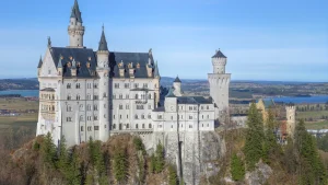 Toàn cảnh Lâu đài Neuschwanstein với các tháp nhọn cổ tích ngự trên đỉnh đồi rừng thông hùng vĩ dãy Alps
