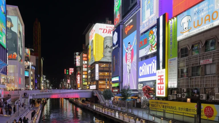 Biển quảng cáo Glico Man chạy đua rực rỡ ánh đèn neon phản chiếu xuống kênh Dotonbori nhộn nhịp