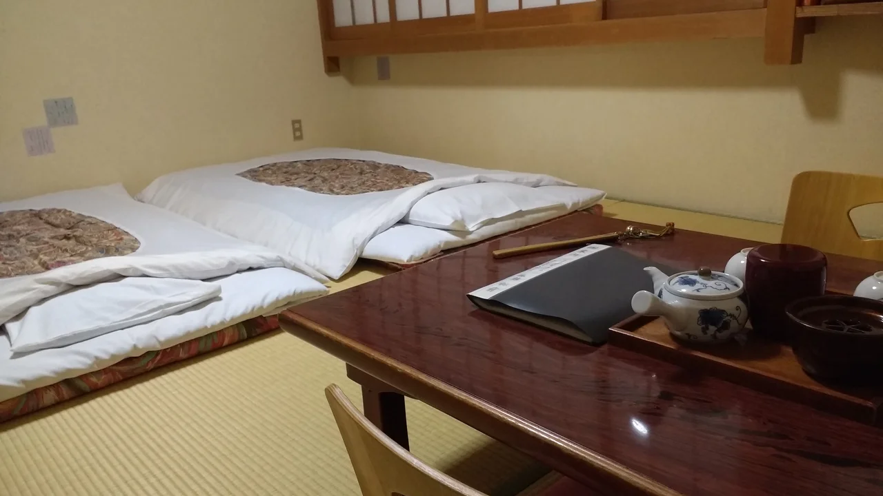 Không gian phòng nghỉ truyền thống Ryokan với sàn chiếu cói Tatami, bàn trà đạo và cửa lùa Shoji thanh tịnh tại Nhật Bản